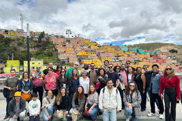 A large group of Summer Institute participants pose for a photo in front of colourful buildings in Bogota, Colombia.